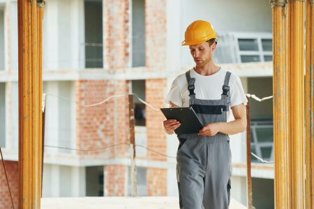 Indoors in the room. Young man working in uniform at construction at daytime